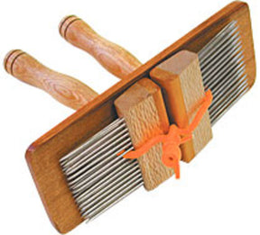 The Majacraft Combs by Majacraft Co. are crafted from New Zealand hardwoods and feature two rows of metal teeth with dual wooden handles. An orange string secures the middle section, holding the comb sides together, making it ideal for preparing wool fibers for spinning.