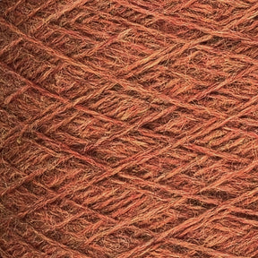 Close-up of a ball of JaggerSpun Heather 3/8 yarn from Jagger Brothers, Inc. The brownish-orange wool yarns are tightly wound, with visible strands and fibers creating a textured surface. The color varies subtly, giving a rustic, earthy appearance. The overall look is warm and cozy.