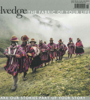 A group of people adorned in traditional Andean attire stroll together in a line along a misty, grassy mountainside. Their vibrant ponchos and hats catch the eye, and several carry woven bags laden with items. The tranquil, mystical ambiance is reminiscent of the scenes featured in Selvedge - Issue 98: Together, a tribute to rich textiles and heritage published by Selvedge.