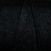 A close-up of black yarn wound tightly in a ball. The texture and individual strands of Maurice Brassard's Cotton 8/8 Carpet Warp are clearly visible, showcasing its thickness and smoothness. Perfect for knitting and crochet projects, the black color appears deep and consistent throughout the yarn.