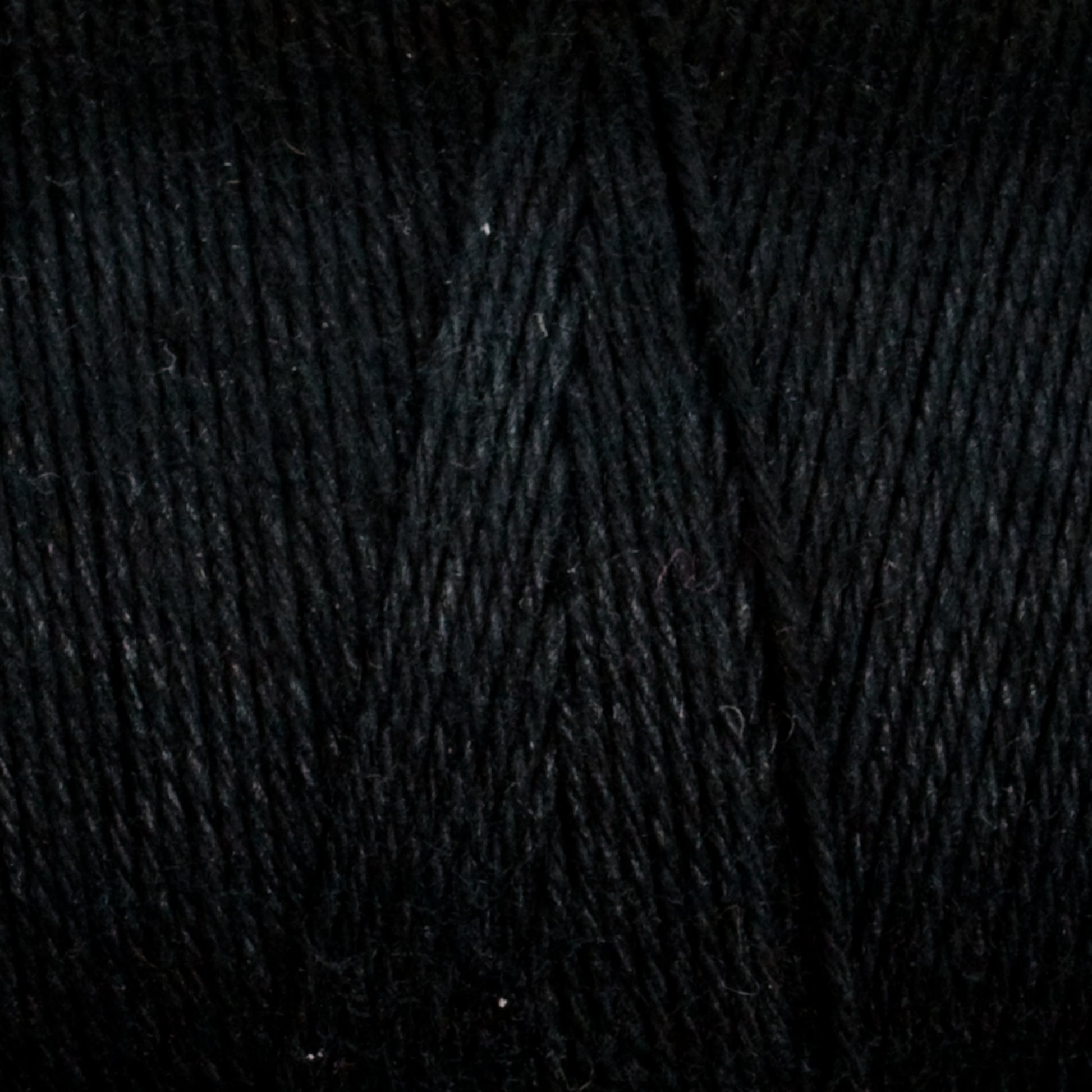 A close-up of black yarn wound tightly in a ball. The texture and individual strands of Maurice Brassard's Cotton 8/8 Carpet Warp are clearly visible, showcasing its thickness and smoothness. Perfect for knitting and crochet projects, the black color appears deep and consistent throughout the yarn.