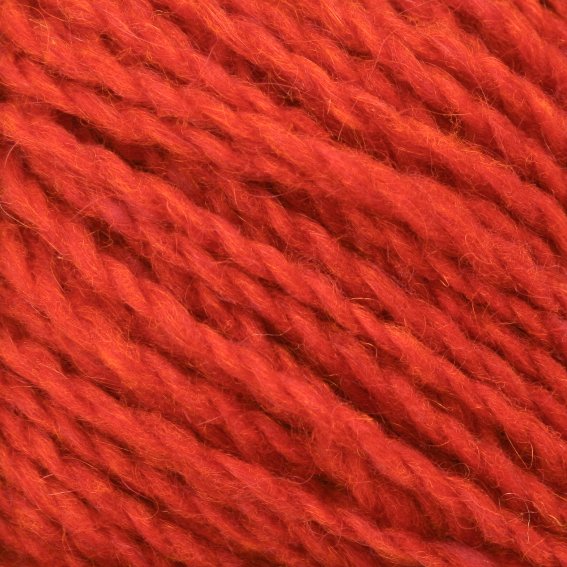 Close-up of a ball of Harrisville Designs Peace Fleece Yarn. The textured fibers of this wool and mohair blend are tightly wound together, showcasing a rich, vibrant color and detail in the strands.