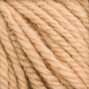 Close-up image of light beige Halcyon Yarn Classic Rug Wool from Caledonian Dye Works, showcasing its thick, twisted texture. The strands appear soft and fluffy, forming a dense and intertwined pattern. The color is uniform and consistent throughout the hand-dyed skein, making it perfect for weavers' intricate projects.