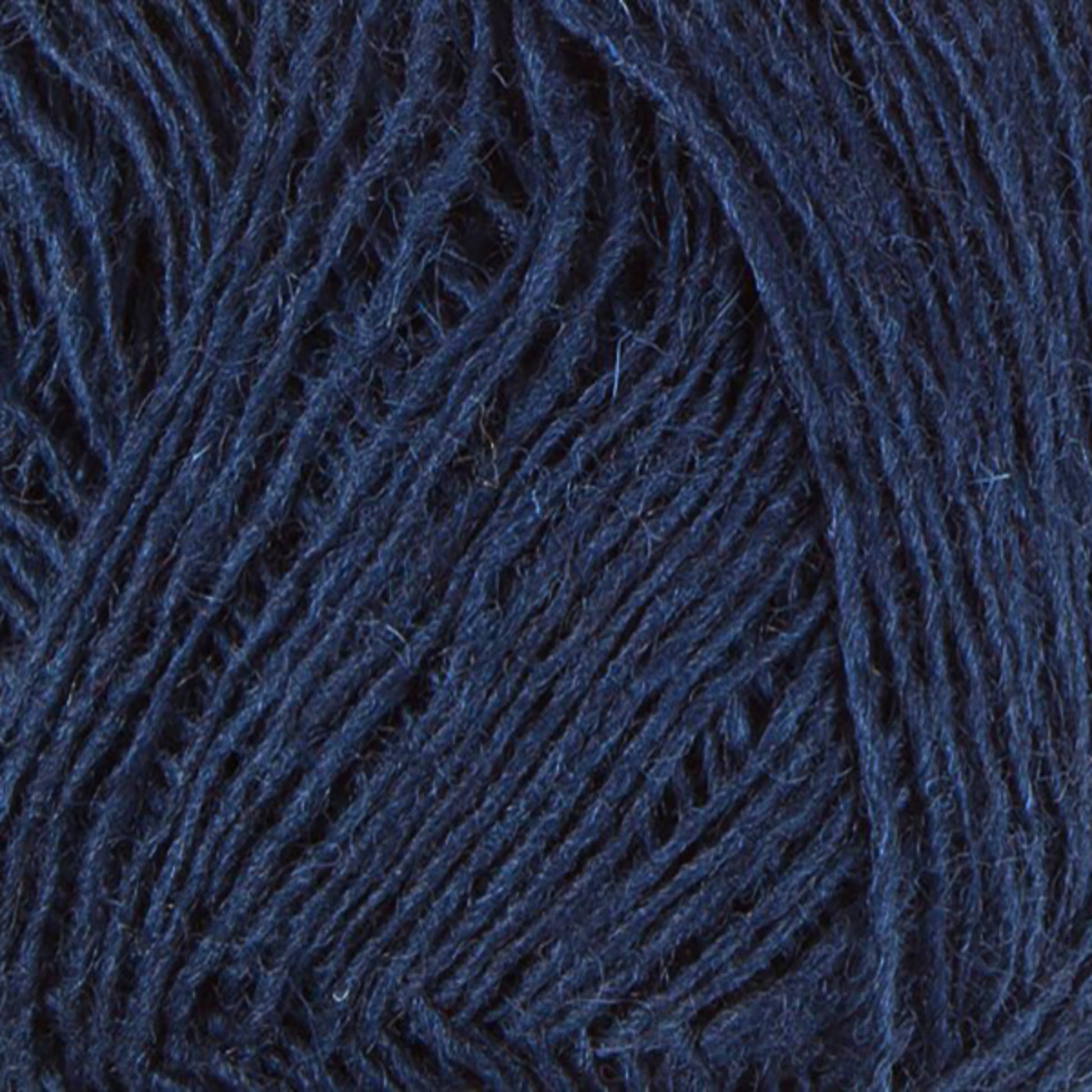 Close-up of strands of dark blue Einband Lopi by Berroco, Inc. The texture appears soft and slightly fuzzy, with the individual fibers visible. The yarn is densely wound together, creating a patterned, intertwined look.