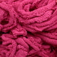 A close-up of a tangled heap of Friendly Loom’s Harrisville Potholder Loops - Traditional Size Mini Pack, showcasing their fibrous texture and intertwined loops reminiscent of those made on a potholder loom. The loops appear soft and densely packed, with various shades of pink visible in the weave.