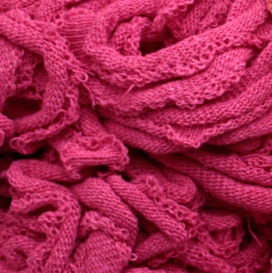 A close-up of a tangled heap of Friendly Loom’s Harrisville Potholder Loops - Traditional Size Mini Pack, showcasing their fibrous texture and intertwined loops reminiscent of those made on a potholder loom. The loops appear soft and densely packed, with various shades of pink visible in the weave.