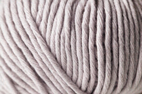 Close-up of a large ball of Jo Sharp Desert Garden Aran Cotton by Kingfisher Yarn & Fibre. The thick strands are tightly wound together, creating a textured surface with visible twists and ridges. This microfibre blend yarn appears soft and ideal for knitting or crocheting projects with exceptional knitting performance.