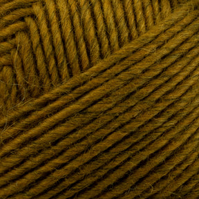 Close-up image of a ball of mustard yellow Lamb's Pride Worsted Yarn by Brown Sheep. The strands are neatly wound, creating a textured pattern. The fibers are slightly fuzzy, ideal for Navajo style weaving or felting projects, adding a soft and artisanal touch.