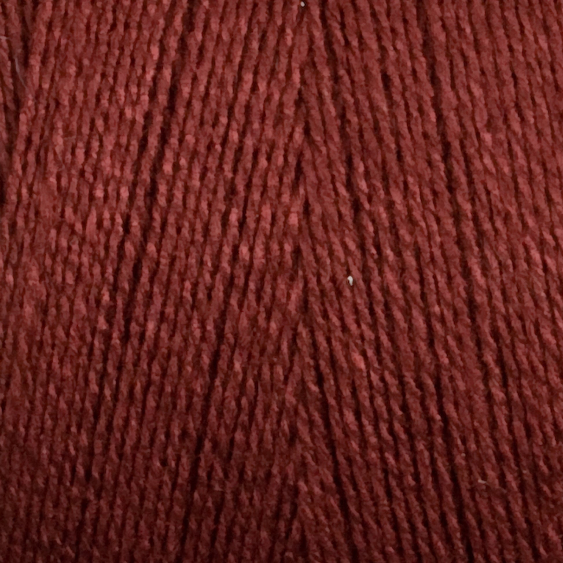 A close-up image of Maurice Brassard's 8/2 Tencel Yarn in soft, dark red. The texture of the yarn strands is clearly visible, displaying a uniform thickness and slightly twisted fibers. The rich and deep color makes it perfect for weaving projects that require a warm and cozy appearance.