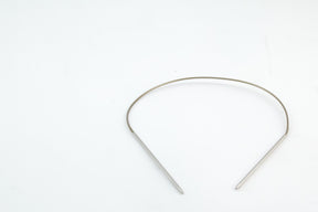 A simple, metallic headband with a thin, curved band and two straight ends is placed against a plain white background. The headband has a minimalist design and appears to be unembellished, similar in elegance to Skacel's Addi Turbo Circular Knitting Needles.