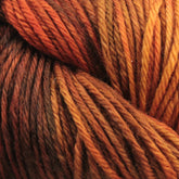 Close-up image of twisted Malabrigo Yarn's Malabrigo Arroyo in warm tones, featuring shades of burnt orange, brown, and gold. The strands are tightly wound together, showcasing a rich, earthy color gradient. The texture is soft and fibrous, perfect for lightweight garments crafted from sport weight superwash merino wool yarn.