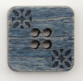 The "Wood Square 3/4" Button" from Buttons Etc. is a wooden button with a blue-grey finish, featuring four centrally placed holes arranged in a diamond pattern. The button, which has softly rounded corners, is adorned with decorative floral carvings in two opposing corners.