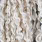 Close-up view of off-white, chunky, textured yarn strands with a mix of twisted and looped fibers. The Lucy Cotton Linen Yarn by Henry's Attic appears soft and loosely spun, creating a tactile and plush appearance.