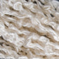 Close-up image of off-white strands from Henry's Attic's Stardust Silk Yarn, featuring chunky weaving yarn fibers intricately intertwined. The texture is soft, fluffy, and slightly shiny, exuding warmth and coziness. The loosely twisted strands create a bulky appearance reminiscent of a gauge swatch with a sett of 8 epi.