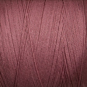 A close-up image of a mini-cone of Maurice Brassard 8/2 Bamboo Yarn. The individual strands are tightly wound, creating a taut, uniform surface that highlights the thin, smooth texture of the yarn. The color is a dusty, muted maroon with subtle variations in shading—perfect for environmentally conscious knitters seeking sustainable alternatives.