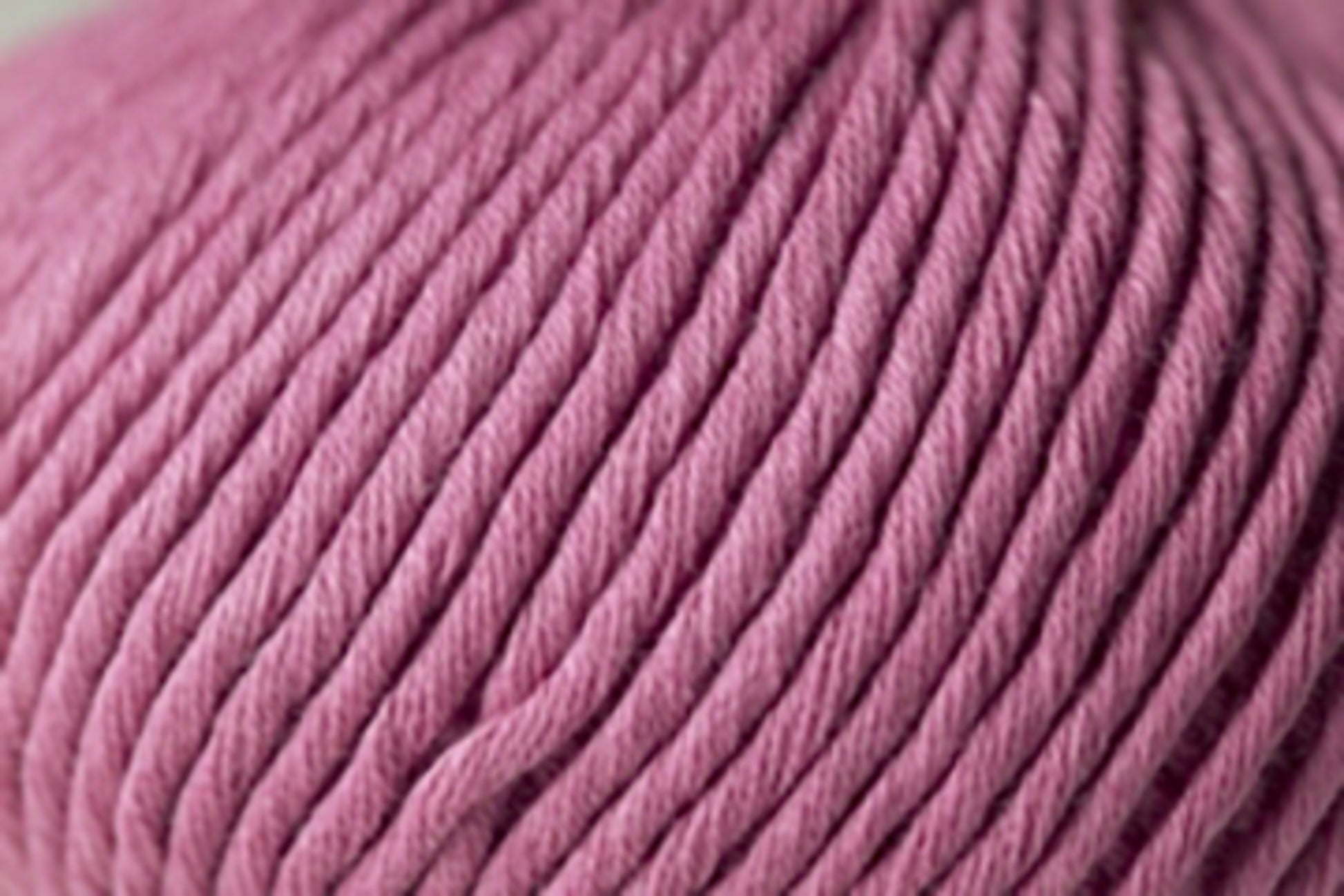 Close-up image of a ball of dusty pink **Jo Sharp Desert Garden Aran Cotton** by **Kingfisher Yarn & Fibre**, showcasing its thick, twisted fibers and soft texture, ideal for knitting performance.