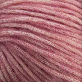 Close-up of soft, luxury Katia Cotton-Merino yarn by Knitting Fever / Euro Yarns in varying shades of light and dark pink strands intertwined. The texture appears fluffy, with individual fibers visible, creating a cozy and warm appearance. This premium aran weight yarn is crafted from Merino wool for added softness and warmth.