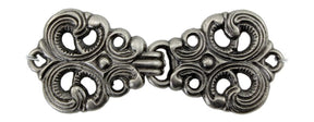 The Scandinavian Style Silver Metal Clasp by Products from Abroad features an intricately designed silver-tone metal clasp boasting symmetrical, ornate patterns and loops on both ends. This accessory has a vintage, antique appearance with curved and swirling details that interlock in the center, making it perfect for adding a touch of elegance to Scandinavian sweaters with one-button closures.