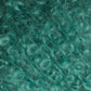 Close-up of a textured surface featuring a mass of curly, teal-colored fibers. The fibers, akin to Victorian Bouclé Mohair Yarn from Caledonian Dye Works, appear soft and fluffy with a slightly shiny appearance, intertwined closely together to create a dense and intricate pattern.