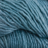 Close-up image of soft, thick Malabrigo Silky Merino yarn strands in light blue, showcasing their texture and twisted fibers. The yarn appears fluffy and slightly shiny, characteristic of Malabrigo Yarn's luxurious blend of natural and synthetic materials. The scene is a macro shot capturing the details of the yarn's composition.