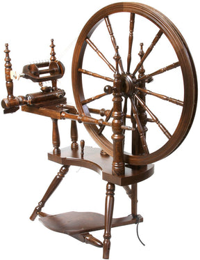 The Kromski Polonaise Spinning Wheel by Kromski North America is a vintage-inspired piece crafted from European alder and birch. It features a large circular wheel connected to a spindle via a horizontal frame, supported by ornate legs and a pedal at the base. Its intricate craftsmanship and polished wood finish exemplify classic design elements.