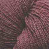 A close-up image of a ball of Patagonia Organic Merino yarn by Juniper Moon Farm. The dark maroon texture is tightly wound, showcasing the detailed fibers and slight variations in color. Made from Organic Merino Wool, the yarn has a soft and slightly fuzzy appearance. This high-quality product is offered by Knitting Fever / Euro Yarns.