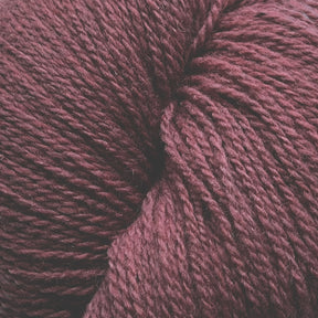 A close-up image of a ball of Patagonia Organic Merino yarn by Juniper Moon Farm. The dark maroon texture is tightly wound, showcasing the detailed fibers and slight variations in color. Made from Organic Merino Wool, the yarn has a soft and slightly fuzzy appearance. This high-quality product is offered by Knitting Fever / Euro Yarns.