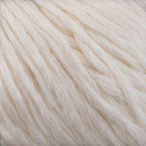 Close-up of soft, ivory-colored Cumulus Cotton by Juniper Moon Farm fibers. The cotton is textured and appears fluffy and thick, with a slightly uneven, natural finish. Its durable chainette construction gives it a warm, cozy feel while being perfect for weightless accessories from Knitting Fever / Euro Yarns.