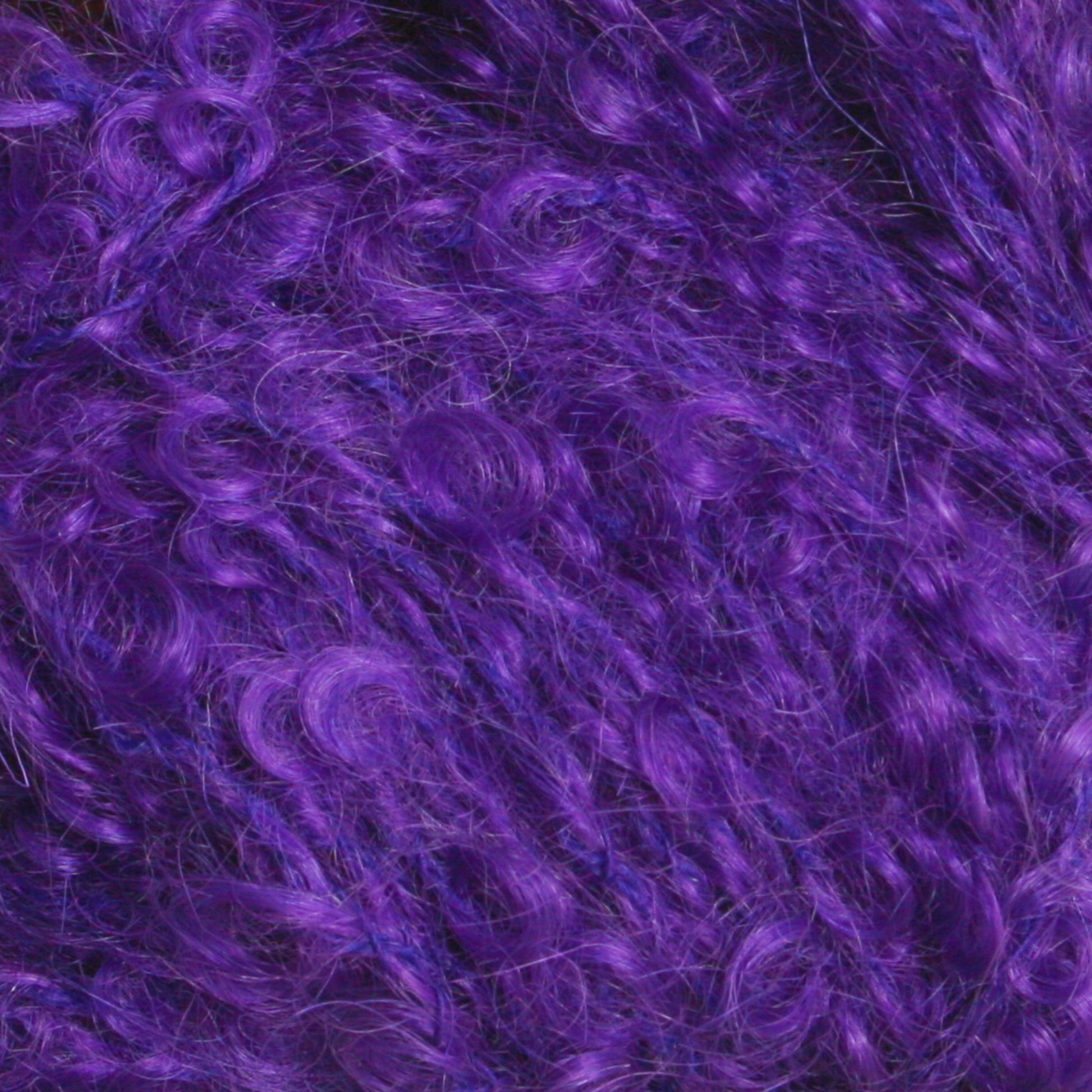 The image displays a close-up of curly, textured yarn in a vibrant purple color. The intertwined fibers create a dense, fluffy, and somewhat unruly appearance. Part of Caledonian Dye Works' Victorian Bouclé Mohair Yarn collection, this mohair bouclé's rich, bold hue stands out, giving it a dynamic and lively look.