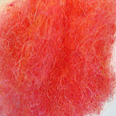 Close-up of Harrisville Dyed & Carded Wool Fiber by Harrisville Designs, showcasing a vibrant heathered pink hue. The bright, fuzzy textured material features tangled and intermixed fibers, creating a soft and fluffy appearance enhanced by the lighting.