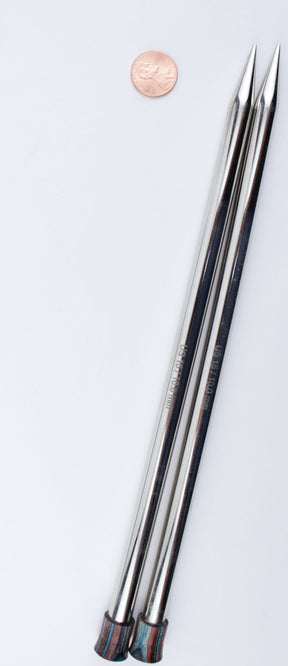 A penny and a pair of Accessories Unlimited Nova Platina Single Point Knitting Needles are placed on a flat white surface. The knitting needles have pointed ends, and their handles are slightly tapered and appear to be made of a different material, possibly wood or plastic.