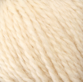 Close-up of a skein of Peace Fleece Yarn by Harrisville Designs. The soft, cream-colored wool and mohair blend appears thick and slightly twisted, giving it a textured look. The fibers are loosely spun, indicating a cozy material suitable for worsted weight knitting projects or crocheting.