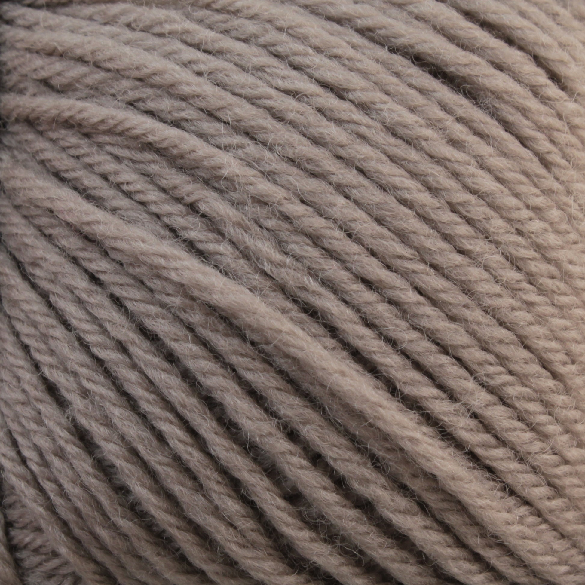 Close-up image of the beige-colored Baby Blatt yarn skein by Essentially Felt Studio & Fine Yarn, revealing the texture of the finely twisted fibers. The strands are tightly wound together, forming a thick and soft bundle suitable for knitting or crocheting projects. This machine washable yarn is ideal for delicate baby garments.