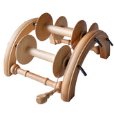 The Kromski Lazy Kate Arch from Kromski North America is a wooden yarn spinning wheel with multiple bobbins and arch-shaped supports, featuring tension control. Designed for spinning ply yarn from fibers, it includes spindles, hooks, and rods to guide and hold the yarn in place. The setup also includes the Kromski Lazy Kate accessory and is set against a white background.