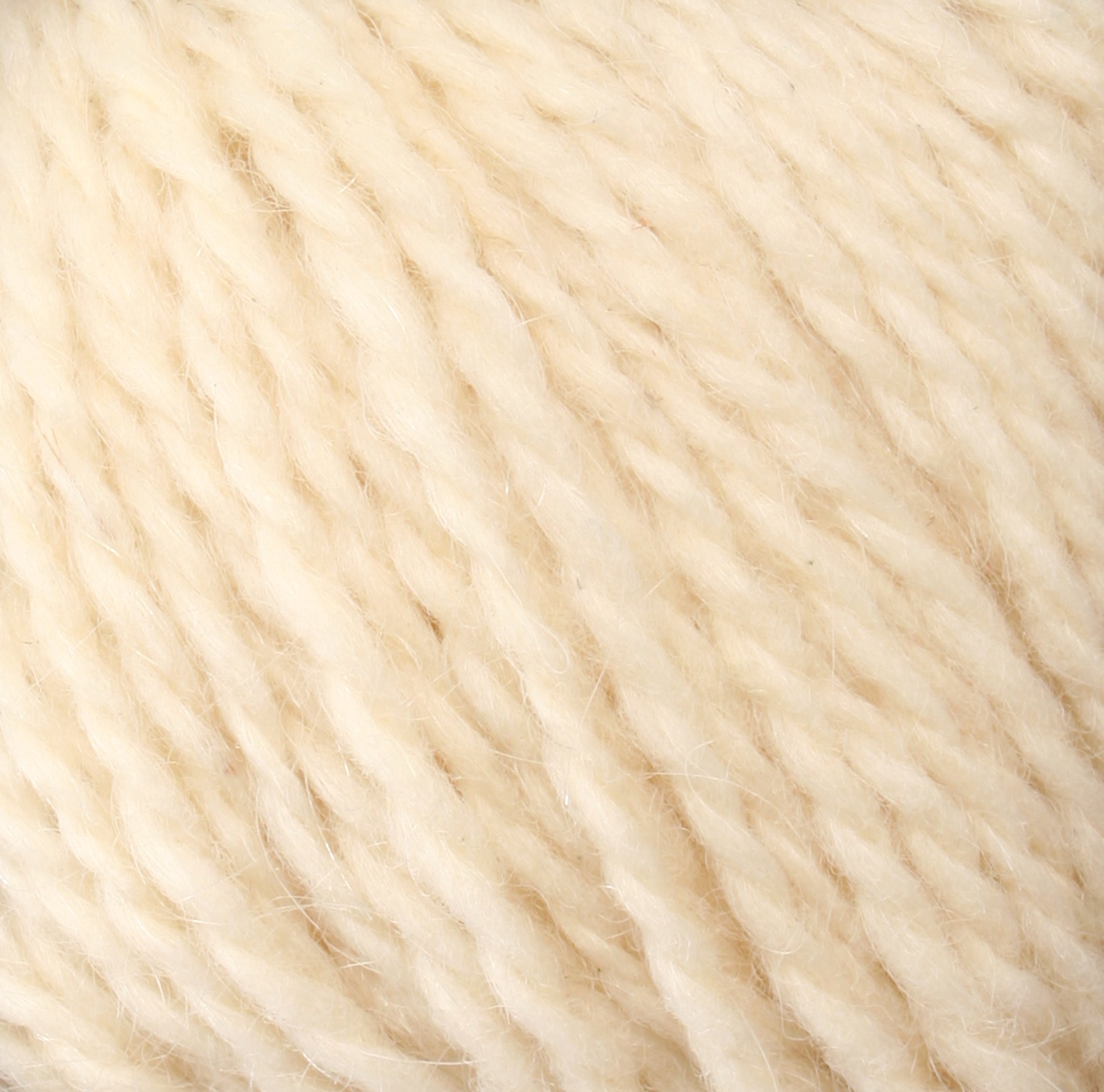 Close-up image of Peace Fleece Yarn by Harrisville Designs. The cream-colored yarn has a softly twisted, slightly fluffy texture, creating a cozy and inviting appearance. This wool and mohair blend showcases a smooth and consistent thickness throughout, making it ideal for worsted weight knitting projects.