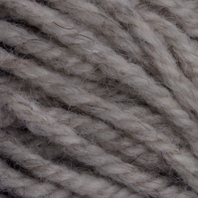 The Halcyon Yarn Classic Rug Wool by Caledonian Dye Works showcases close-up, thick, twisted strands of off-white yarn. The texture is soft and slightly fuzzy, with some individual fibers visible. This natural rug wool appears to be un-dyed, offering variations in thickness and color perfect for weavers seeking authenticity.