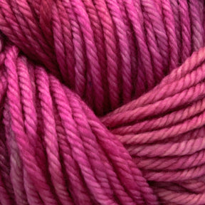 Close-up image of strands of pink and magenta Malabrigo Rios yarn from Malabrigo Yarn, tightly wound together. The yarn showcases a gradient of dark and light shades, giving a soft texture and a vibrant, rich color palette. The texture of the fibers is clearly visible, highlighting the kettle-dyed colors and twists.