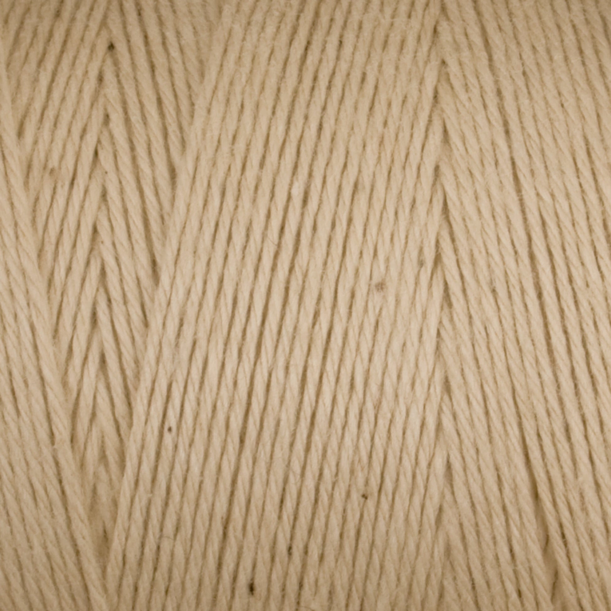 Close-up image of Maurice Brassard's Medium Cotton 16/8 Mop Yarn in beige, showcasing its soft texture and tightly wound strands. Ideal for knitting, weaving, and other crafts, this sturdy cotton yarn appears smooth and evenly spun. Small variations in color and texture can be seen, adding to its natural look.