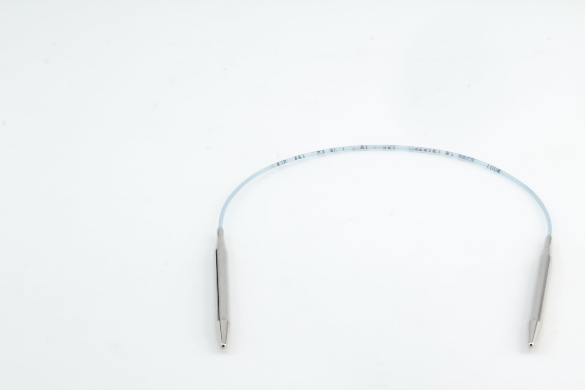 A flexible medical instrument with a blue-tinted tube and metal tips on both ends, positioned in a slight curve on a plain white background, showing precision reminiscent of Skacel's Addi Turbo Circular Knitting Needles.