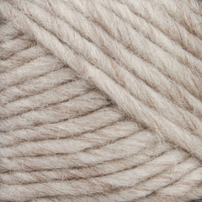 Close-up of a ball of Brown Sheep's Lamb's Pride Bulky Yarn with visible fiber texture. The thick, cream-colored yarn strands are wound tightly together, showcasing a subtle mix of beige and off-white hues—ideal for knitters and crocheters crafting Icelandic sweaters.