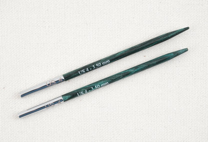 Two green-tinted wooden Dreamz Interchangeable Knitting Needle Tips by Accessories Unlimited feature smooth joins with metal connectors and are labeled "US 4 - 3.50 mm" in white text on their surface. The needles, perfect for knitting hats, are placed parallel to each other against a light beige, textured fabric background.