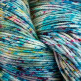 Close-up image of Malabrigo Sock yarn by Malabrigo Yarn, showcasing a mix of light blue, teal, white, and specks of pink, yellow, and purple. The soft, thick strands are densely wound together, highlighting their rich texture and vibrant speckled pattern. This luxurious yarn is also machine washable.