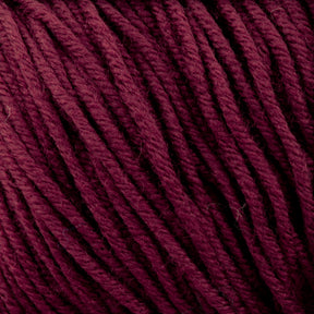 Close-up of the dark red Plymouth Select Worsted Merino Superwash yarn strands from Plymouth Yarn Co., intricately intertwined in a ball, showcasing the detailed fibers and texture. The yarn boasts a rich, deep hue and is tightly wound, highlighting its structure and thickness. Its superwash quality ensures excellent stitch definition for your projects.