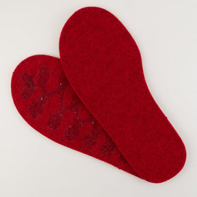 A pair of Joe's Toes Children's Thick Felt Slipper Soles with Latex Grip in red, one placed slightly on top of the other, are displayed on a plain white background. The top sole is smooth, while the bottom one reveals a textured underside with some adhesive remnants.