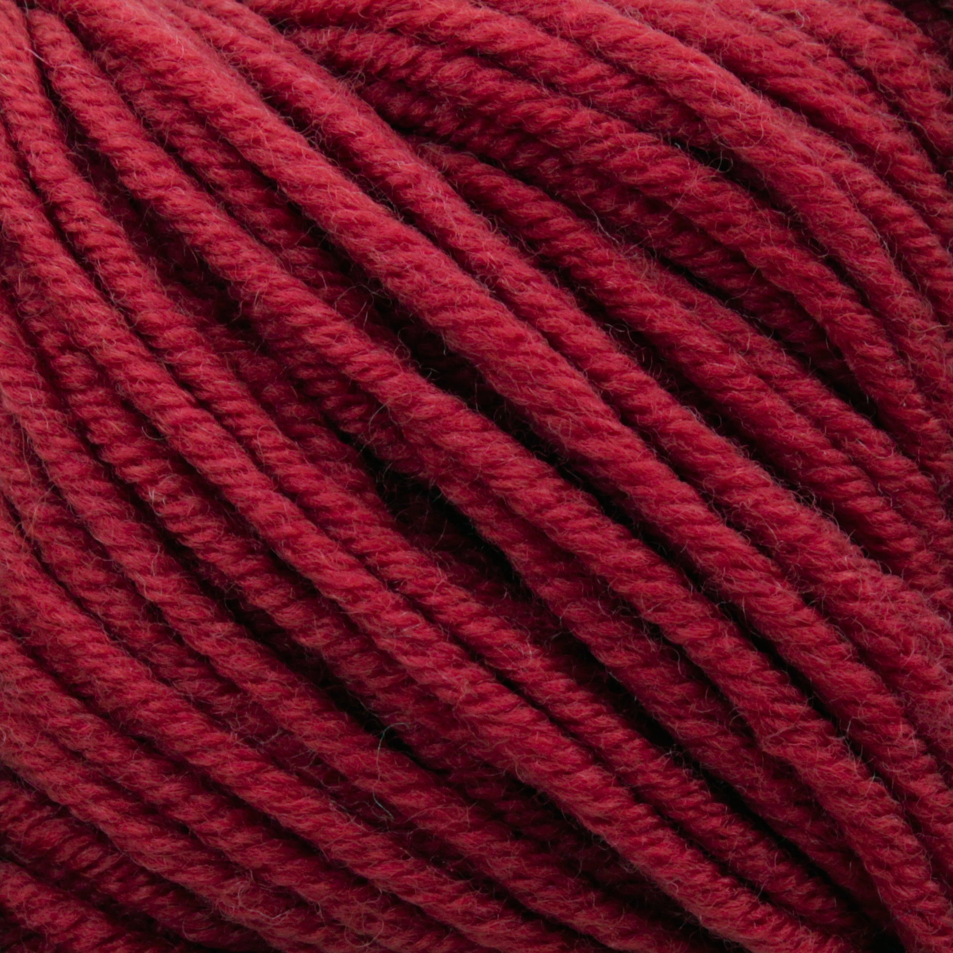 Close-up image of thick, red yarn from Plymouth Yarn Co.'s Plymouth Select Worsted Merino Superwash, showing individual strands tightly wound together. The texture appears soft and slightly fuzzy, suggesting the yarn is ideal for knitting or crocheting cozy garments or accessories with excellent stitch definition.