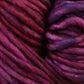 Close-up image of soft, thick Malabrigo Mecha yarn with hues blending from deep burgundy to rich purple. The kettle dyed texture appears smooth and slightly fuzzy, showcasing the cozy and vibrant quality of the superwash bulky yarn fibers from Malabrigo Yarn.