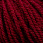 Close-up of thick, twisted strands of deep red Aran weight Norumbega yarn by Caledonian Dye Works. The texture of the 100% U.S. wool is soft and fibrous, with visible strands braided together to form a cohesive and dense bundle. The rich, vibrant color is consistent throughout the durable fabric.