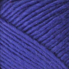 A close-up image of Brown Sheep's Lamb's Pride Worsted Yarn in deep blue, showcasing the texture and weave of the fibers. The yarn appears thick and slightly fuzzy, with individual strands tightly bundled together. The background features a continuous pattern of this luxurious yarn.