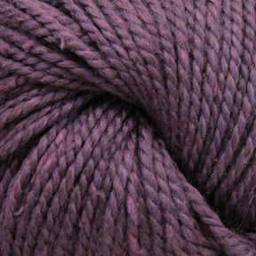 Close-up of thick, twisted Acadia by The Fiber Company yarn in shades of purple and lavender, showing the individual fibers and textures. The strands are tightly wound together, showcasing a rich blend of colors with a subtle tweed effect and a soft, fuzzy appearance.