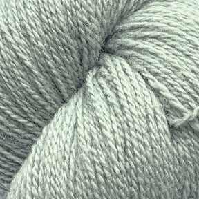 Close-up of light grey yarn. The image shows the texture and twisted strands of Patagonia Organic Merino by Juniper Moon Farm, highlighting its soft and slightly fuzzy appearance. The yarn, from Knitting Fever / Euro Yarns, is tightly wound and fills the entire frame with a consistent color and thickness throughout. GOTS certified for quality assurance.